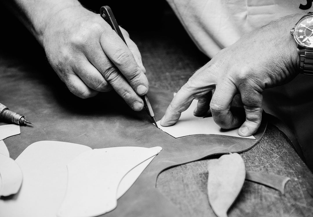 Manueller Lederzuschnitt anhand einer Schablone – traditionelles Schuhhandwerk bei Sioux in Schwarz-Weiß.