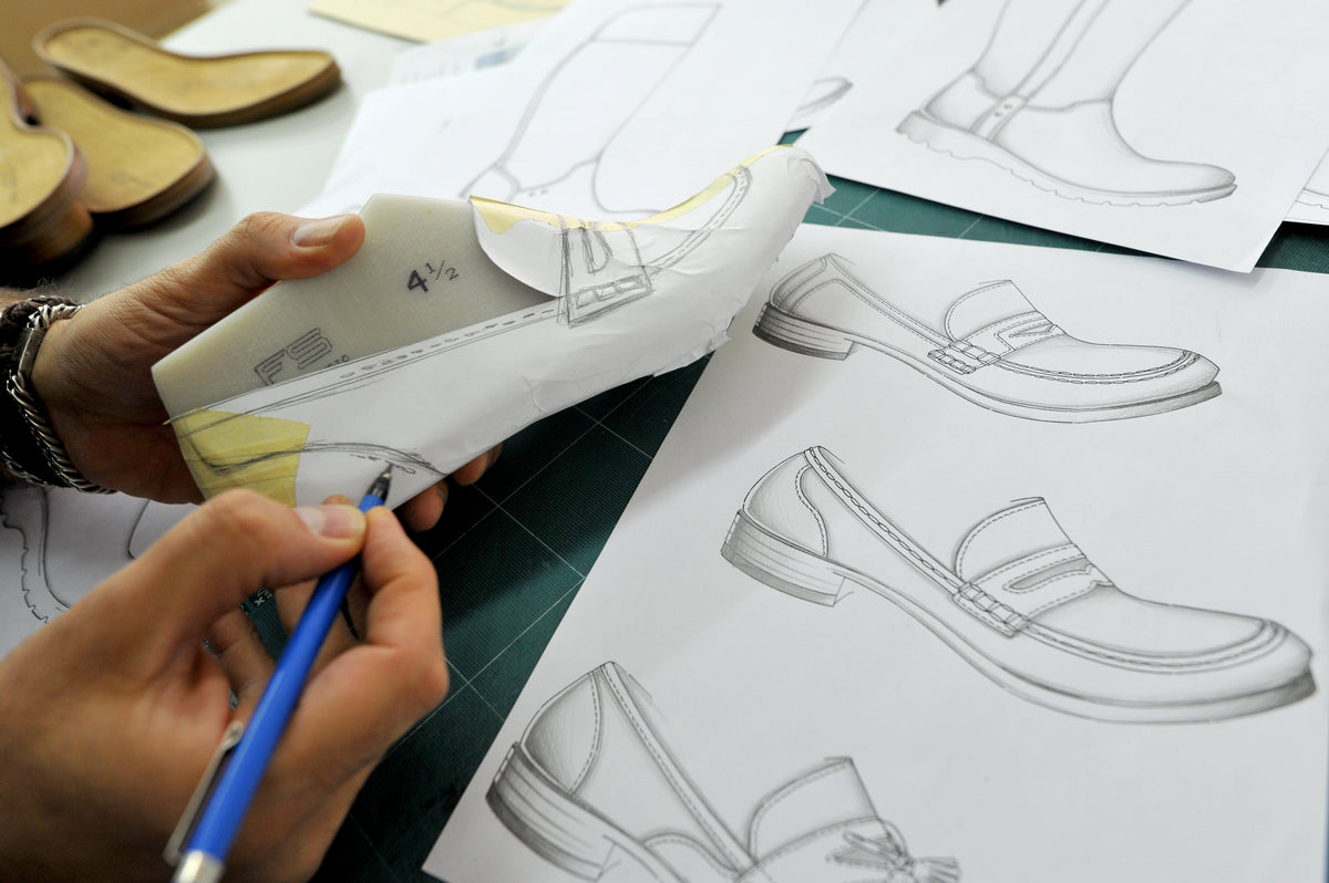 Hände zeichnen ein Schuhmodell auf einem Leisten, daneben liegen technische Skizzen zur Sioux Modellentwicklung.
