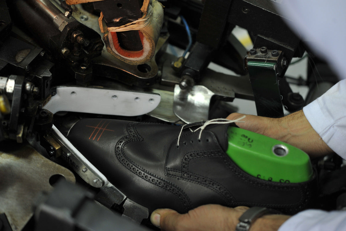 Herstellung eines schwarzen Sioux Lederschuhs in AGO-Machart auf dem Schuhleisten an einer Produktionsmaschine.